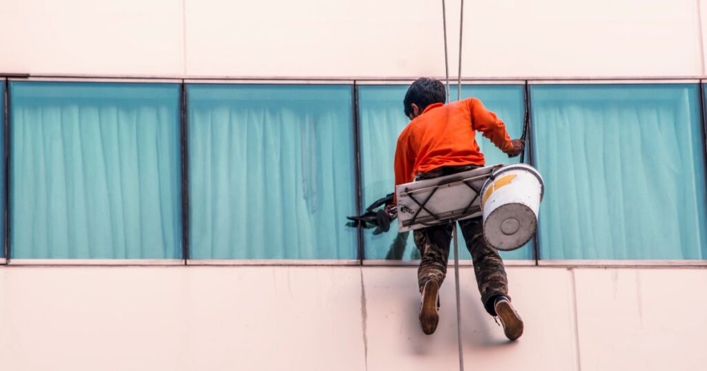 Manutenção Predial de Condomínios - homem fazendo manutenção da fachada de um prédio
